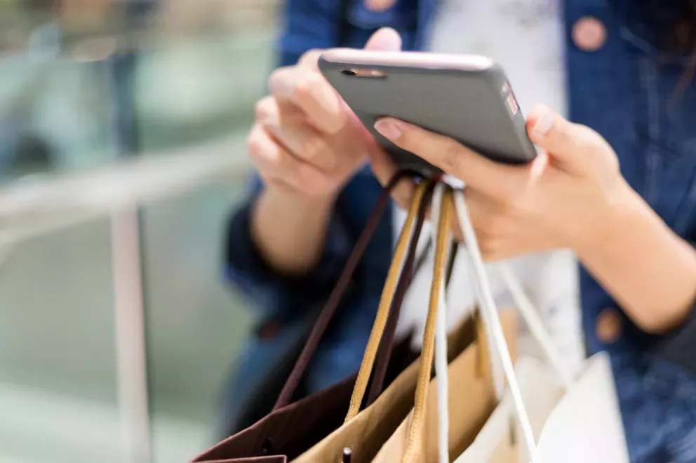 close up of person using cell phone holding shopping bags close up of person using cell phone holding shopping bags