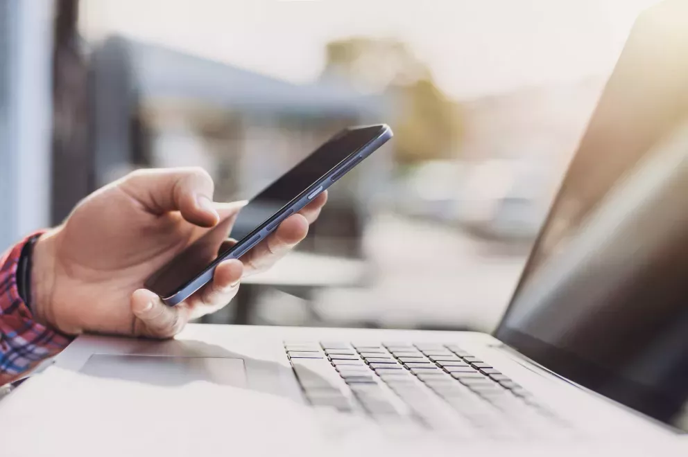 close up of person using cell phone and laptop close up of person using cell phone and laptop