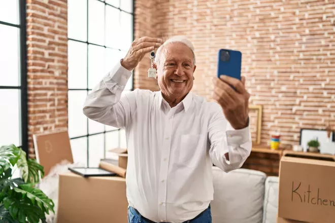 excited man holding new house keys up to phone to take selfie excited man holding new house keys up to phone to take selfie