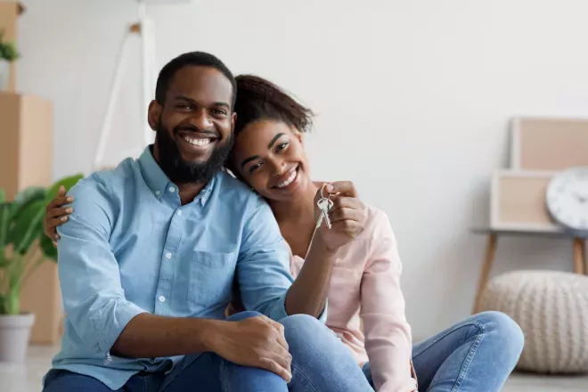 Smiling couple holding up keys to new home Smiling couple holding up keys to new home