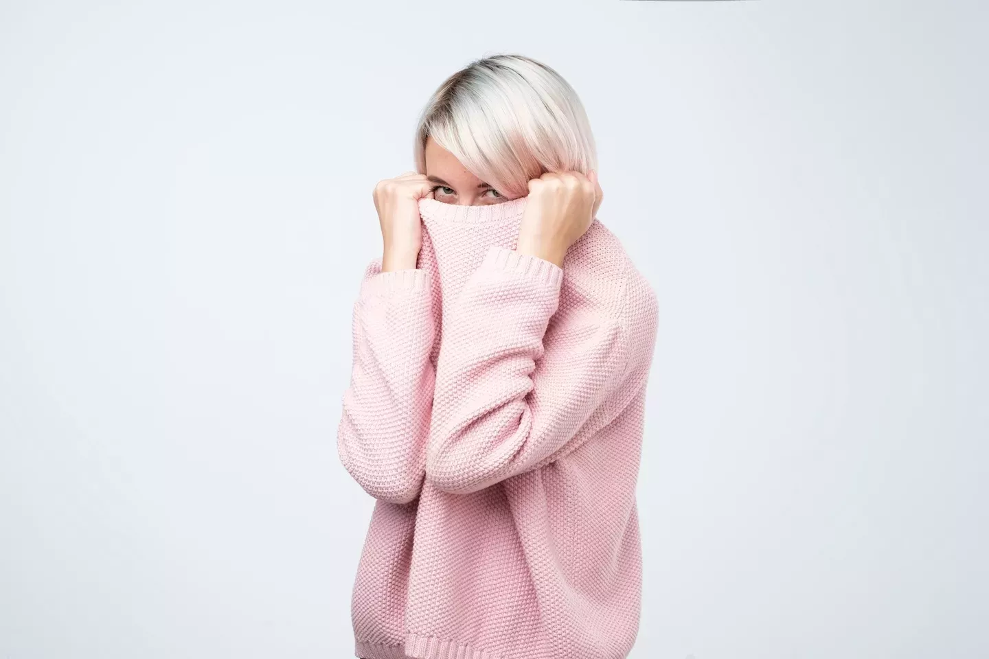 Woman hiding in a pink sweater Woman hiding in a pink sweater