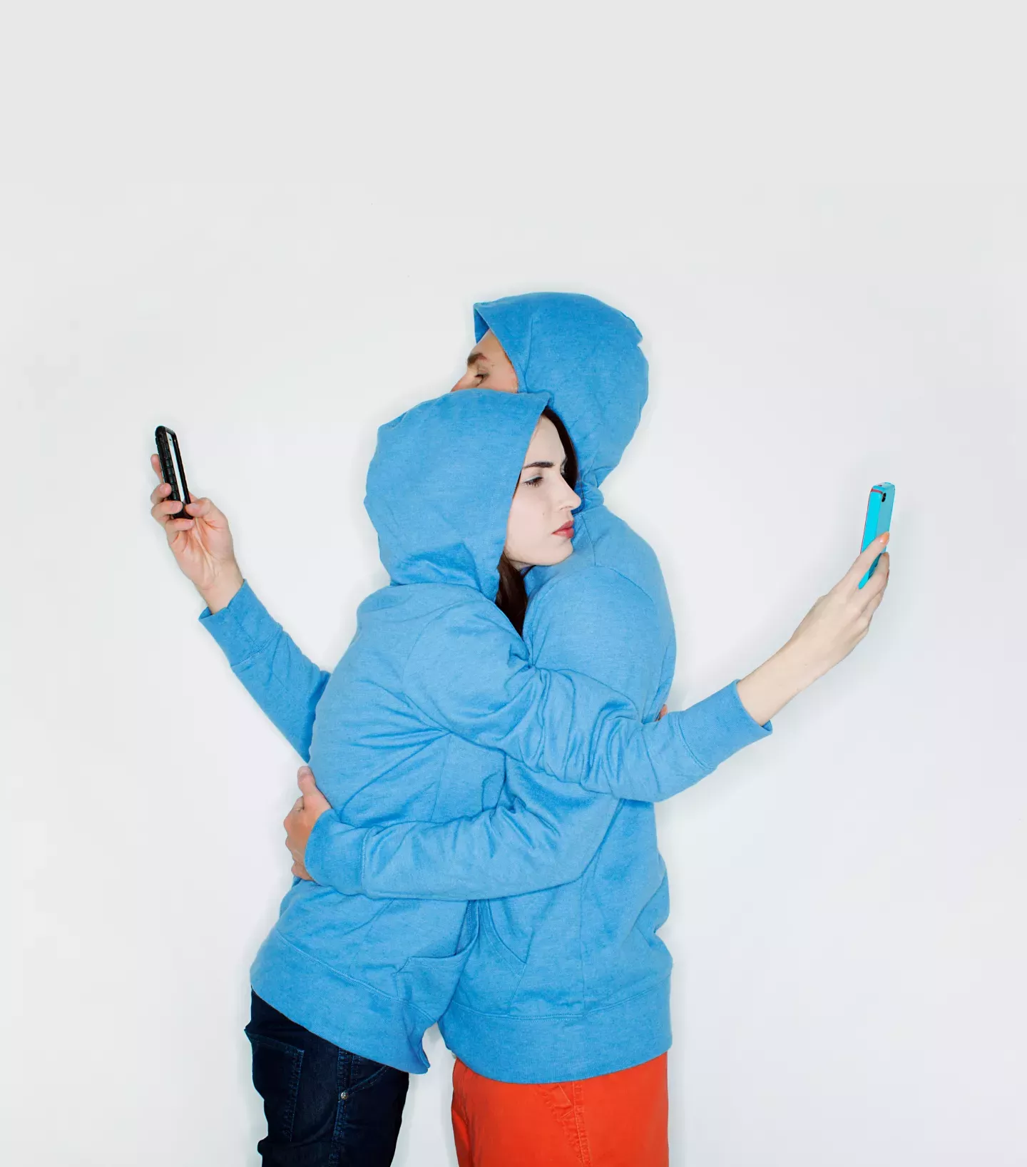 Two people hugging and looking at phones Two people hugging and looking at phones