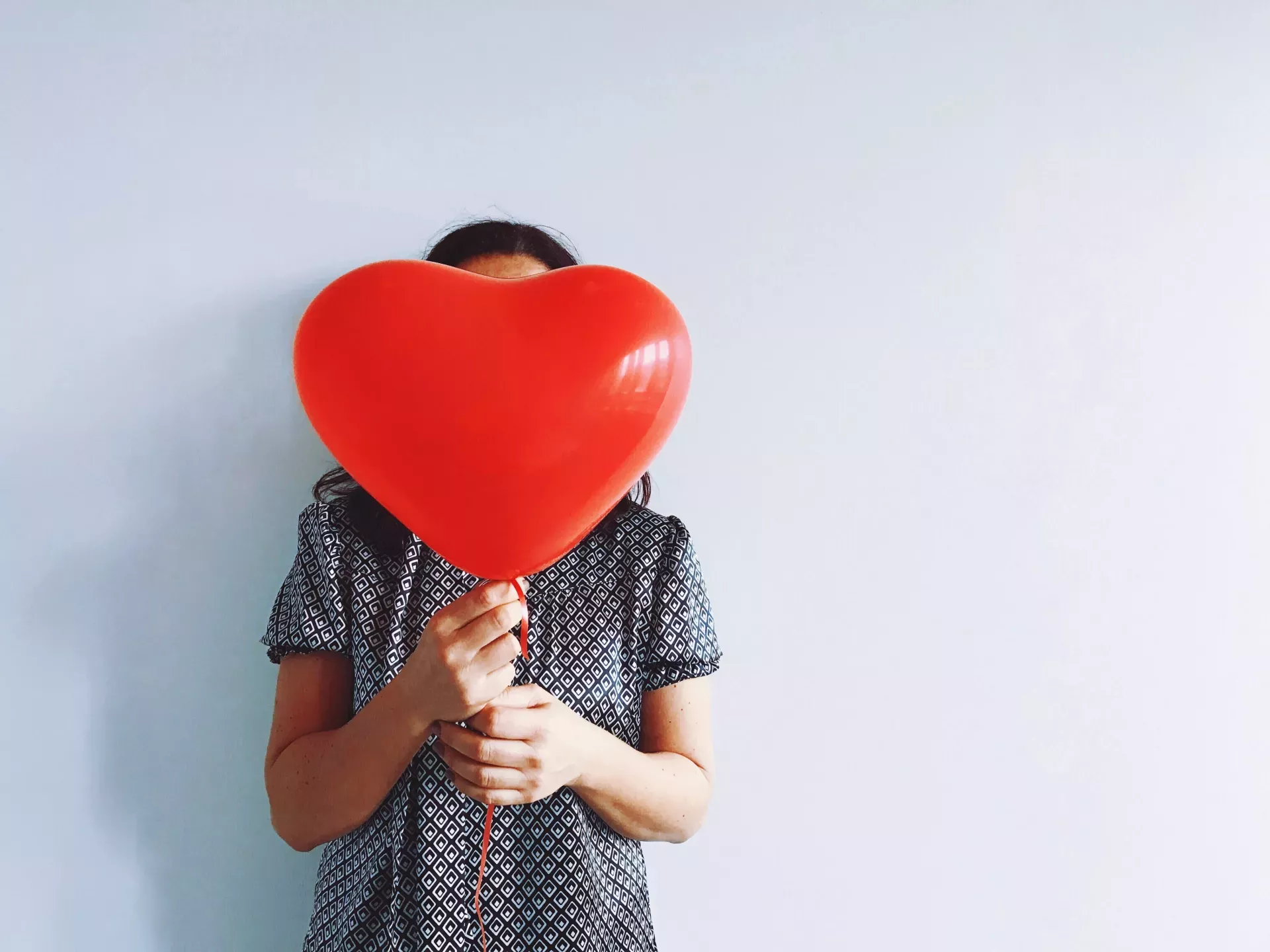 woman holding red heart-shaped balloon woman holding red heart-shaped balloon