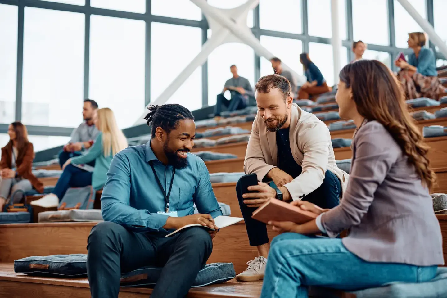 Three diverse college students chatting enthusiastically in a bright, modern lecture hall. Three diverse college students chatting enthusiastically in a bright, modern lecture hall.