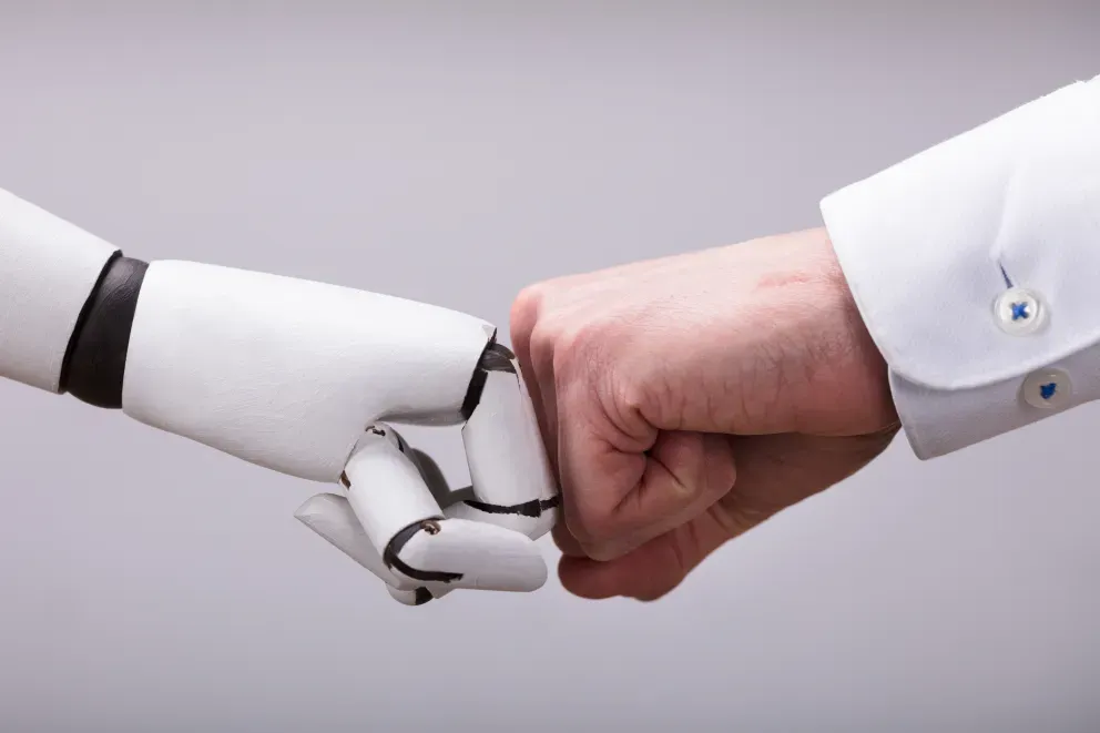close up of human and robot fist bumping close up of human and robot fist bumping