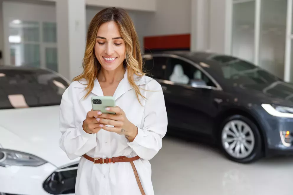 smiling woman customer in car showroom using cell phone smiling woman customer in car showroom using cell phone