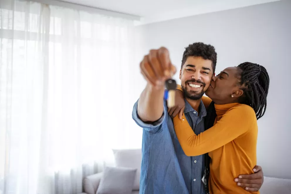 excited couple in new home holding out new keys excited couple in new home holding out new keys
