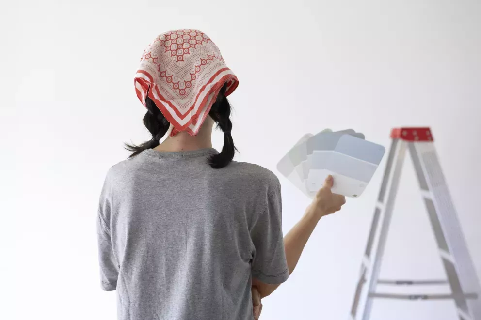 woman looking at blank wall holding paint swatches woman looking at blank wall holding paint swatches