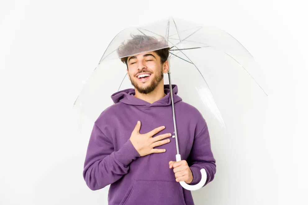 man holding umbrella with relieved expression man holding umbrella with relieved expression
