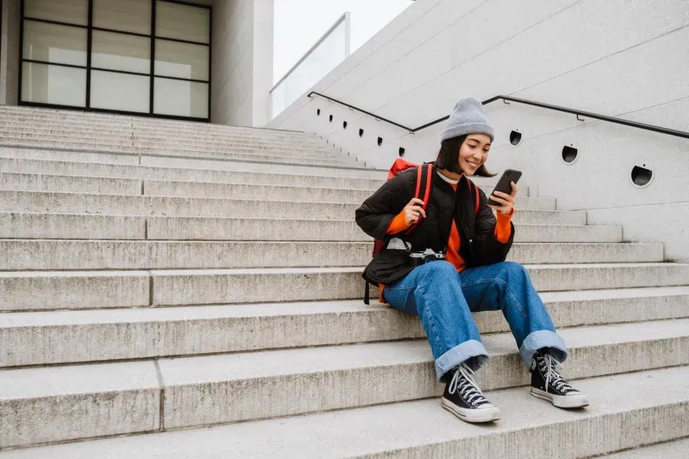 Woman sitting on steps with backpack and phone Woman sitting on steps with backpack and phone