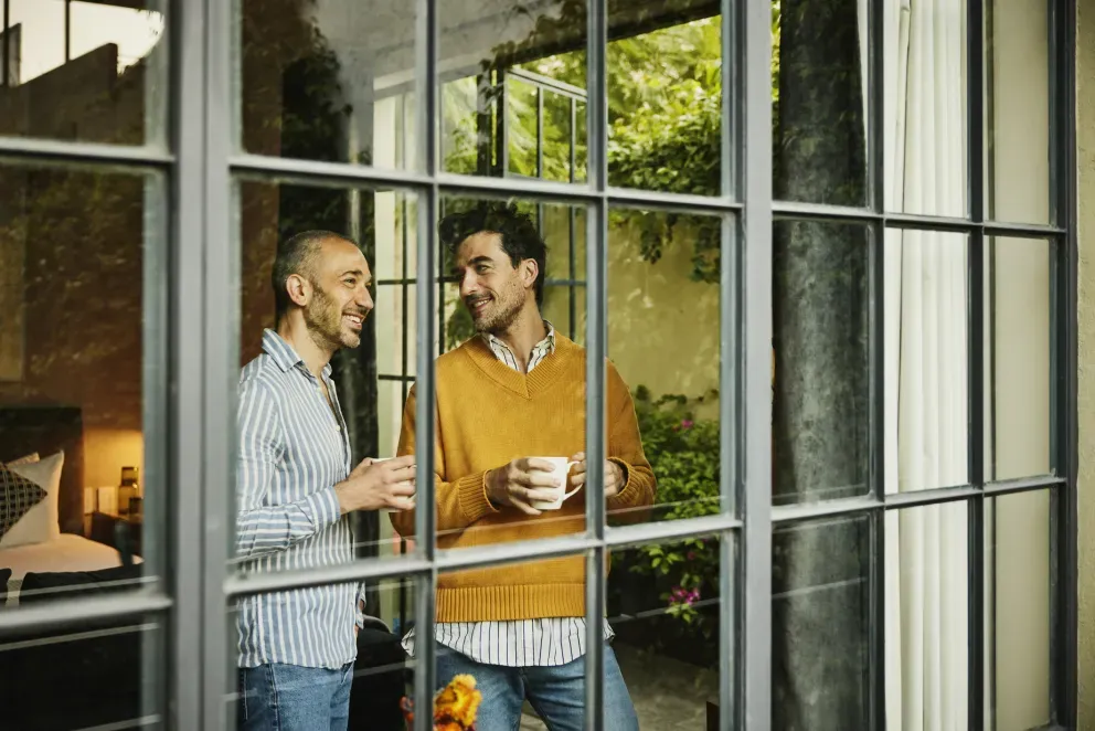 Two men drinking coffee looking out window Two men drinking coffee looking out window