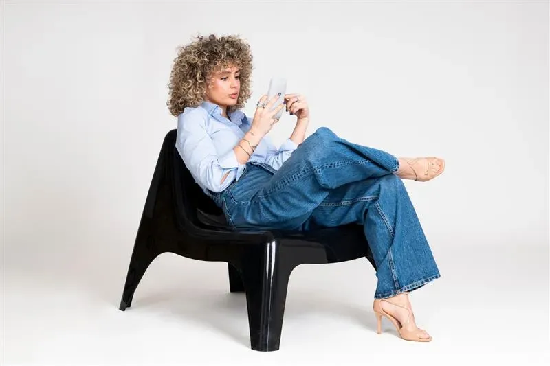 woman sitting cross legged in chair while reading phone woman sitting cross legged in chair while reading phone