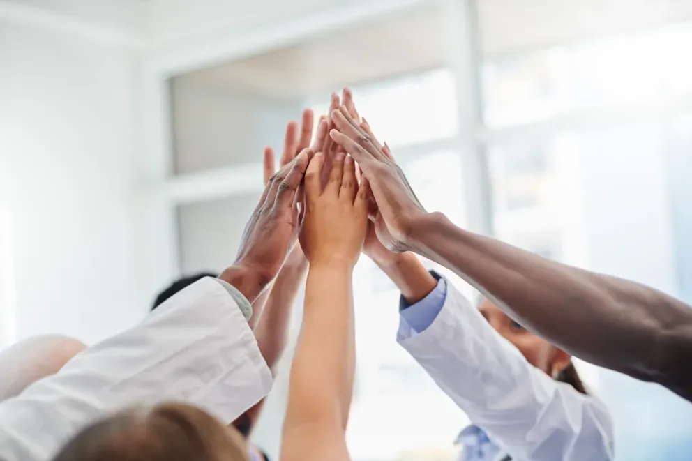 Diverse group of people stacking hands together in a teamwork gesture. Diverse group of people stacking hands together in a teamwork gesture.