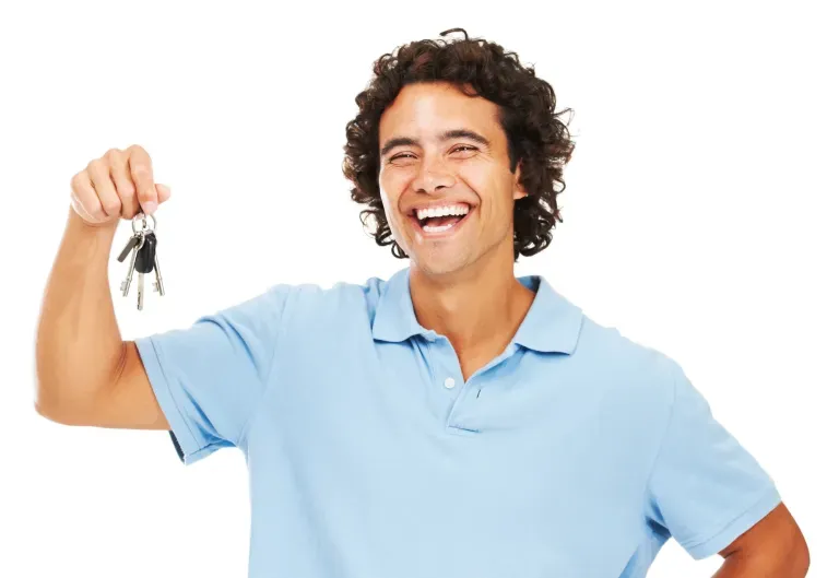 Smiling man in light blue polo shirt holding up house keys Smiling man in light blue polo shirt holding up house keys