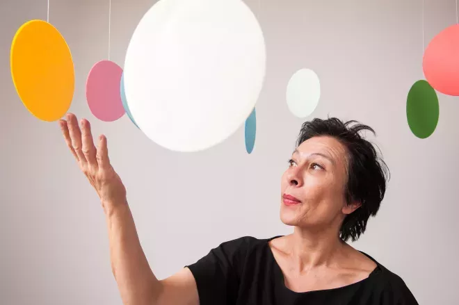 woman standing in the middle of hanging circle art pieces  woman standing in the middle of hanging circle art pieces