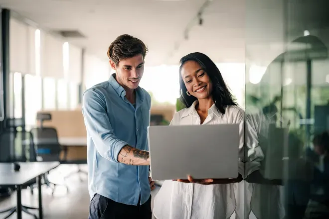 Business man and woman looking at laptop in office Business man and woman looking at laptop in office