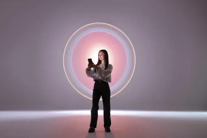 Woman standing in front of a large glowing circular pink and white light installation. Woman standing in front of a large glowing circular pink and white light installation.