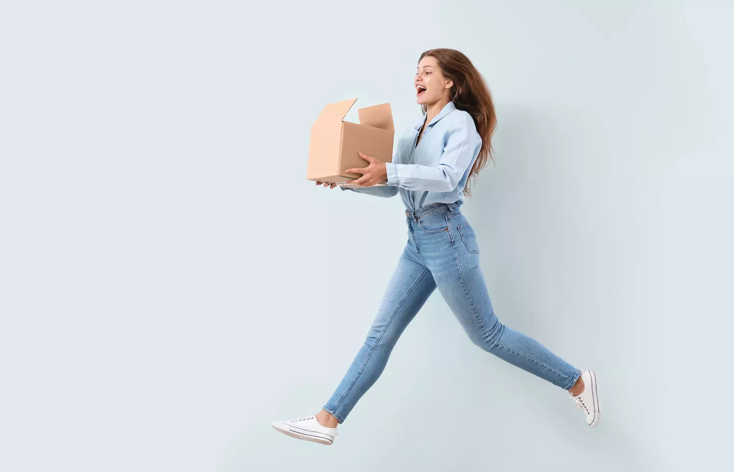 Woman jumping holding a box Woman jumping holding a box
