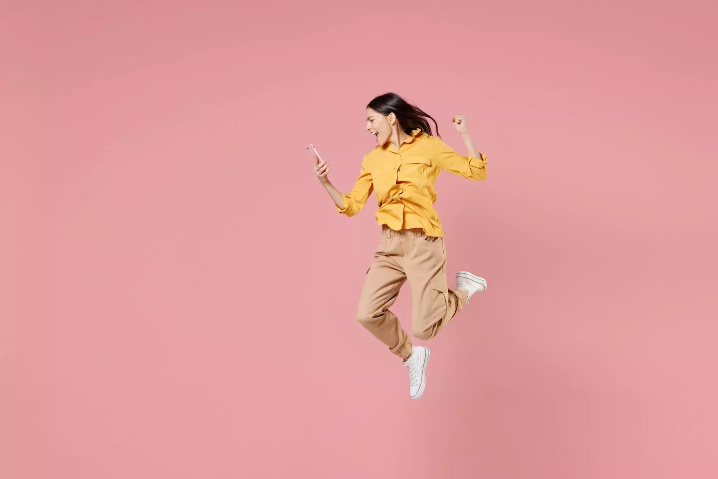 Woman jumping looking at a phone Woman jumping looking at a phone