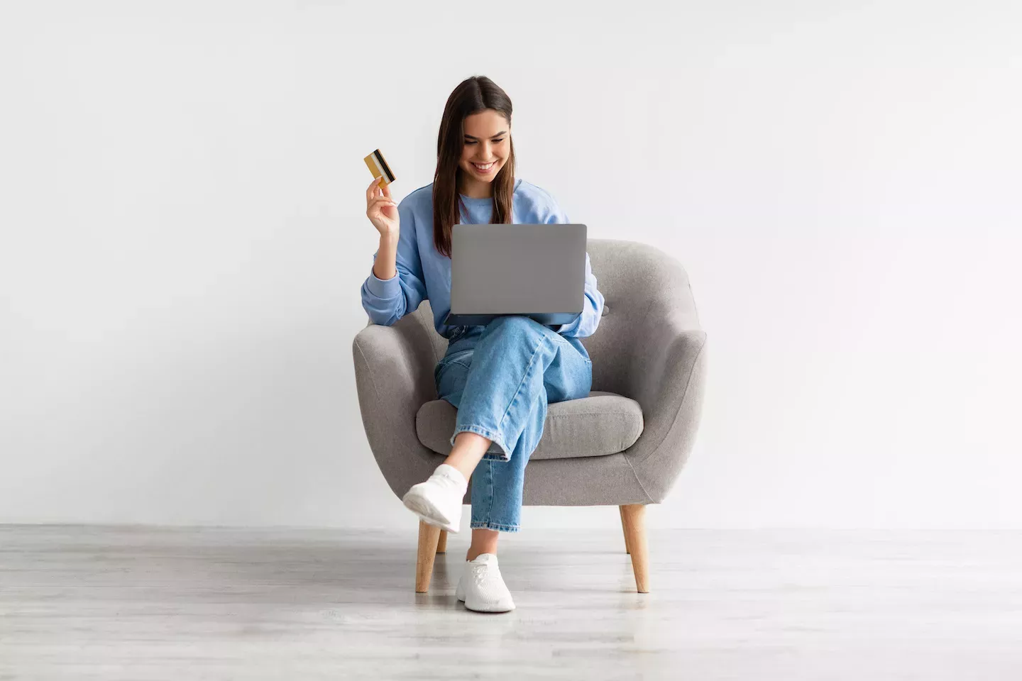 Woman sitting in a chair holding a credit card Woman sitting in a chair holding a credit card