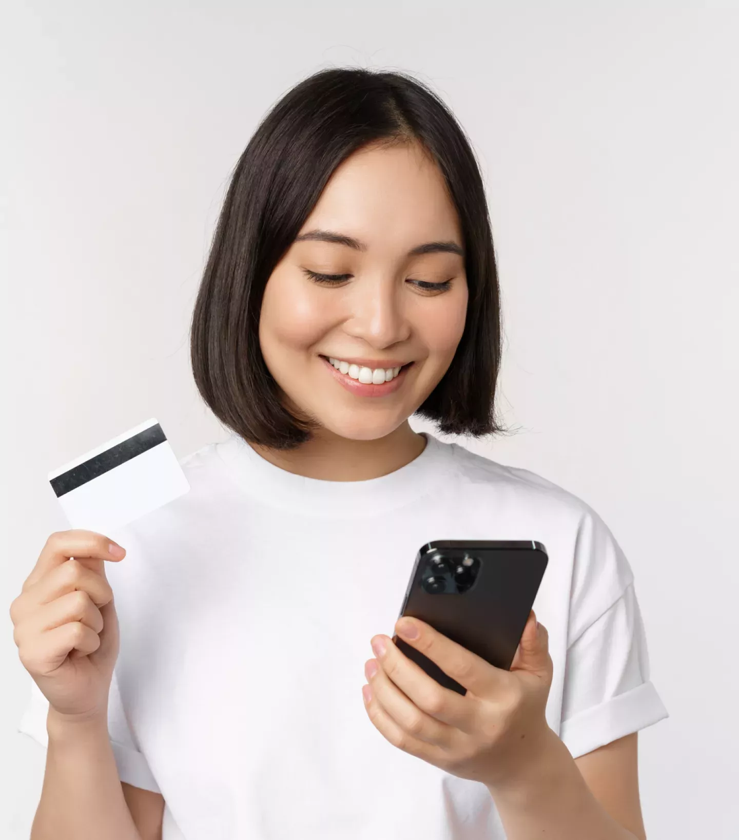 Woman looking at a phone holding a credit card Woman looking at a phone holding a credit card