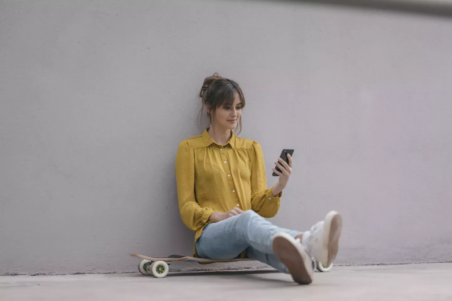woman sitting on longboard looking at cell phone woman sitting on longboard looking at cell phone