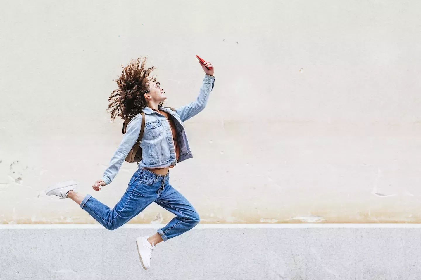 Woman jumping looking at a phone Woman jumping looking at a phone