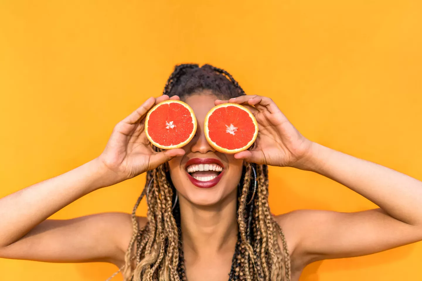 Woman holding two oranges over her eyes Woman holding two oranges over her eyes