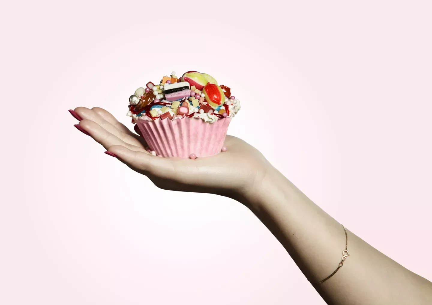 close up of person holding cupcake with candy frosting close up of person holding cupcake with candy frosting