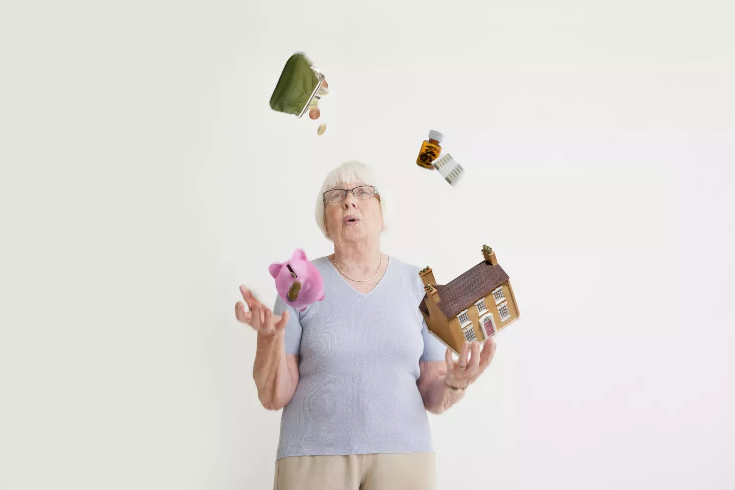 woman juggling piggy bank house purse and medications woman juggling piggy bank house purse and medications