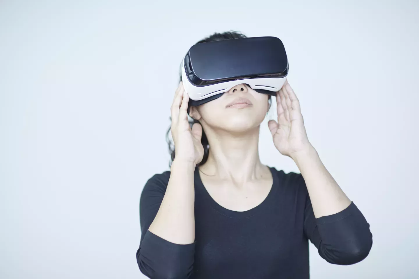 woman holding virtual reality headset to eyes and looking up woman holding virtual reality headset to eyes and looking up