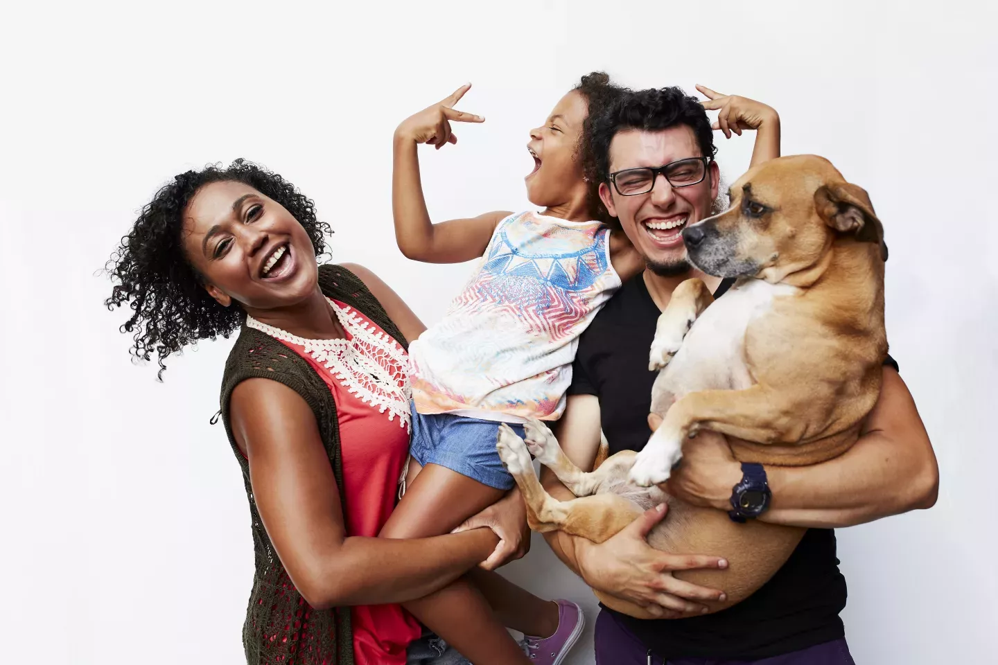 Energetic young family portrait mother holding daughter and father holding puppy Energetic young family portrait mother holding daughter and father holding puppy