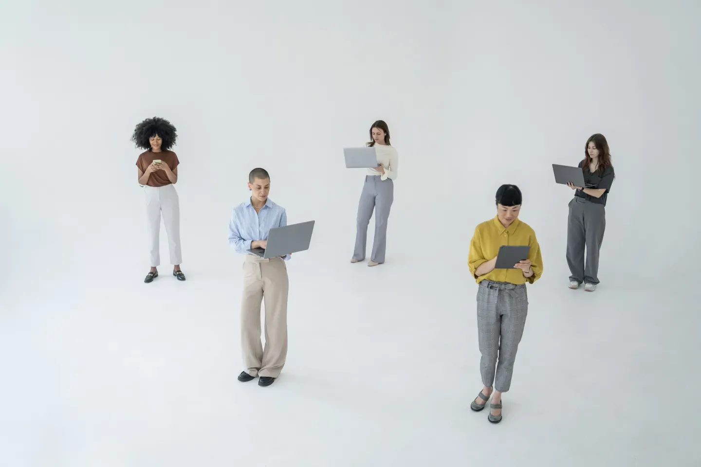 Five small figurines of people in casual clothing scattered on white background Five small figurines of people in casual clothing scattered on white background