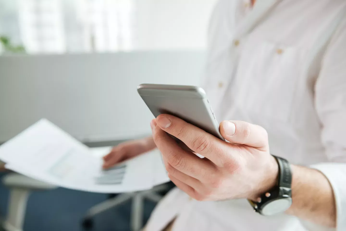Person using a phone and holding papers Person using a phone and holding papers