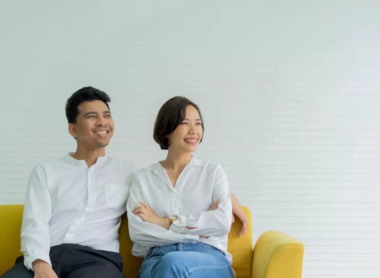 Happy couple sitting on a yellow couch Happy couple sitting on a yellow couch