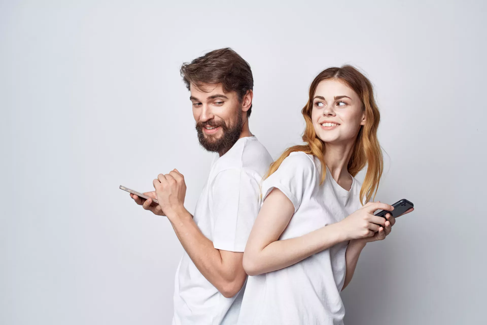 smiling people standing back to back using cell phones smiling people standing back to back using cell phones
