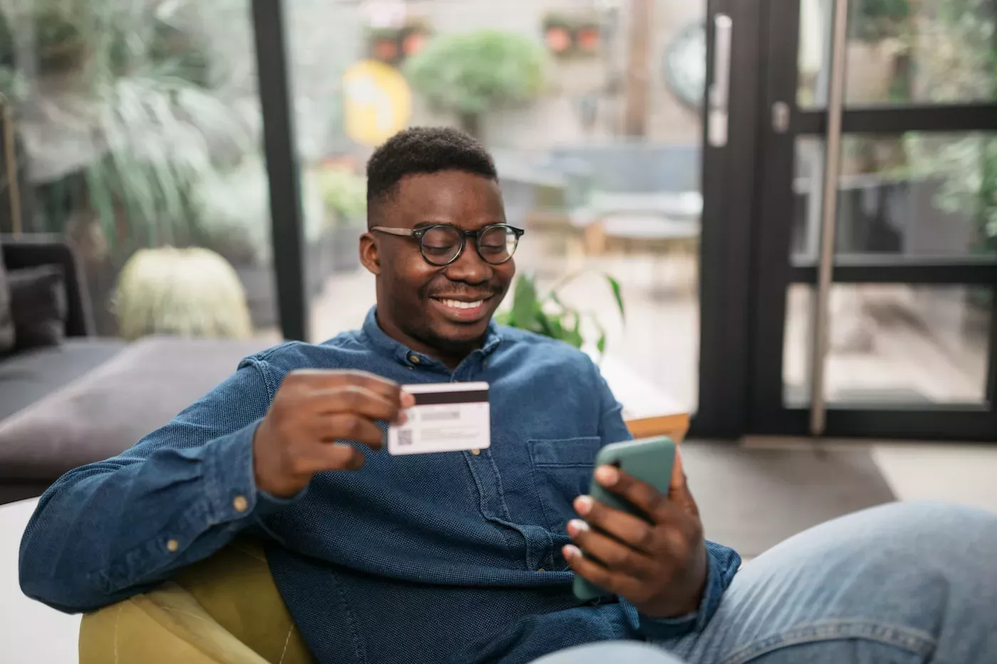 Man looking at a mobile phone and holding a credit card Man looking at a mobile phone and holding a credit card