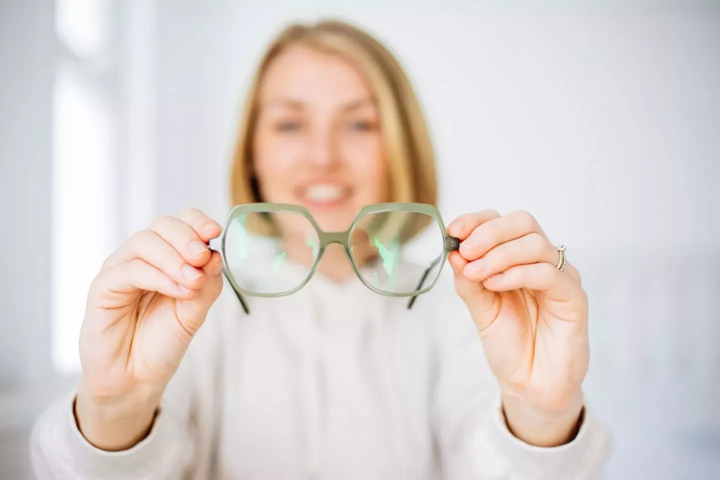 person holding up glasses person holding up glasses