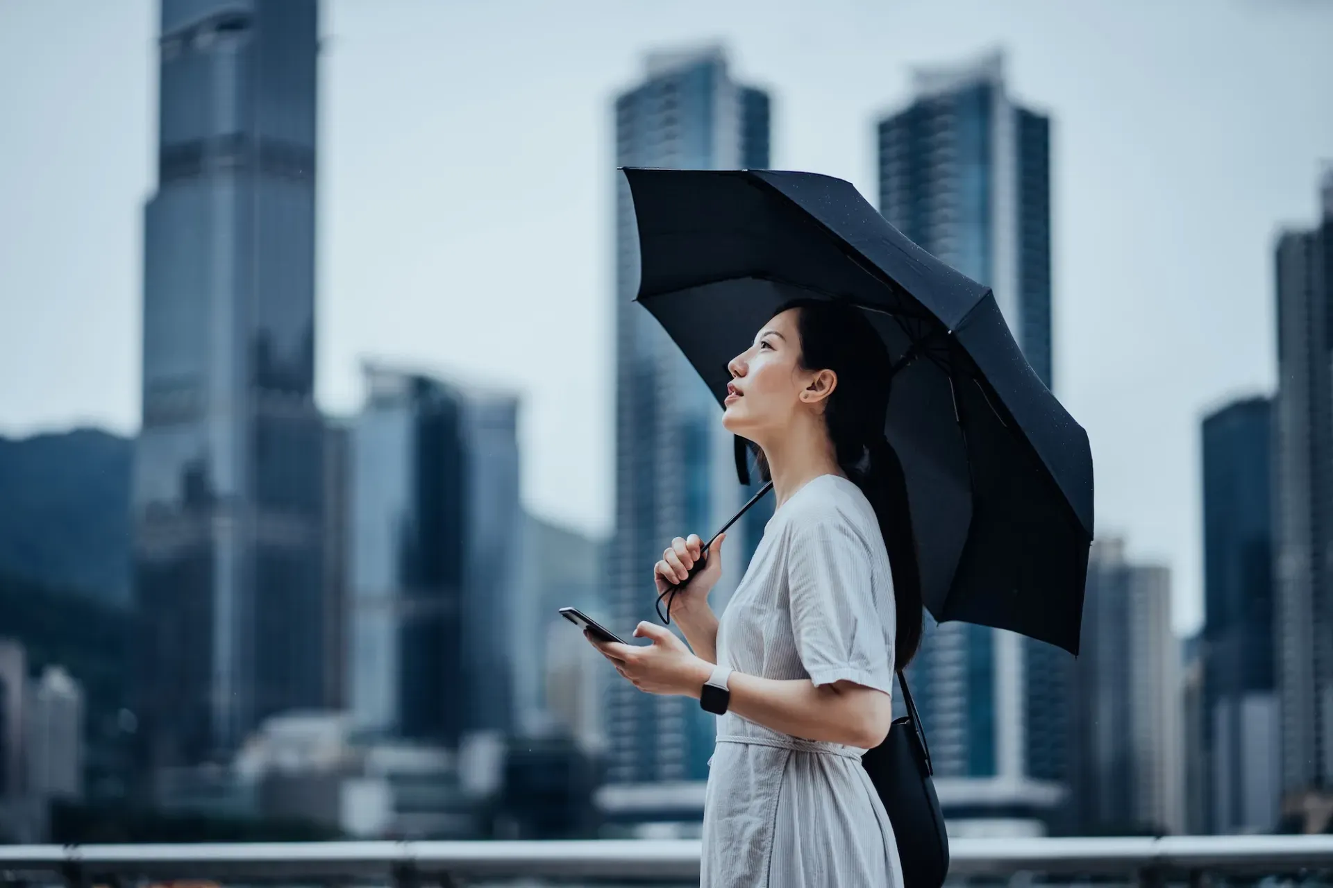 Woman with umbrella and phone in city Woman with umbrella and phone in city