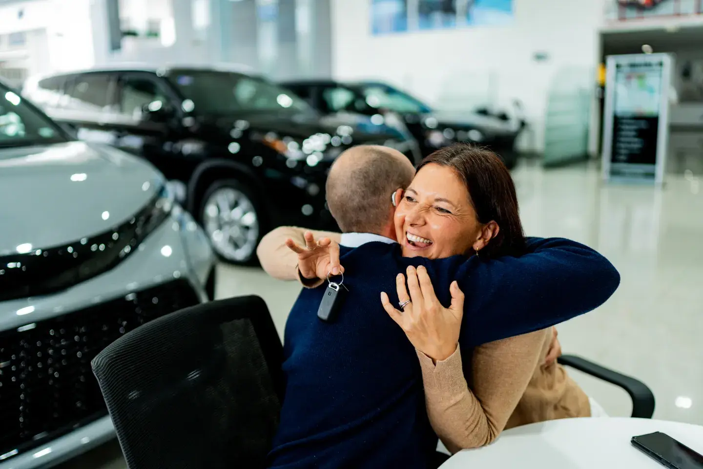 Man and woman hugging at car dealership Man and woman hugging at car dealership